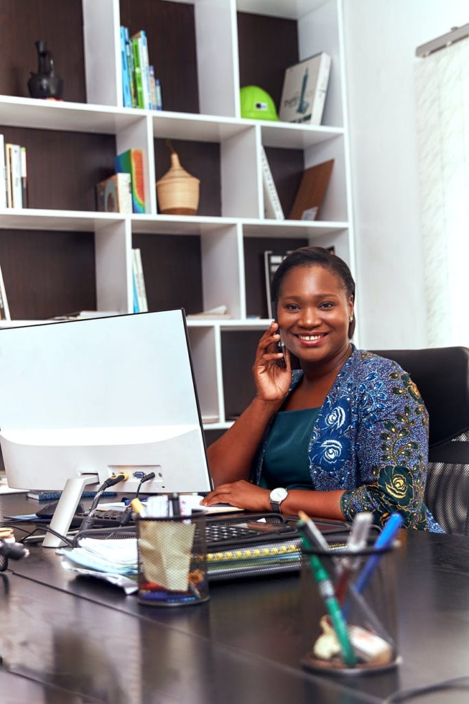 woman sitting in front of a computer while talking on the phone